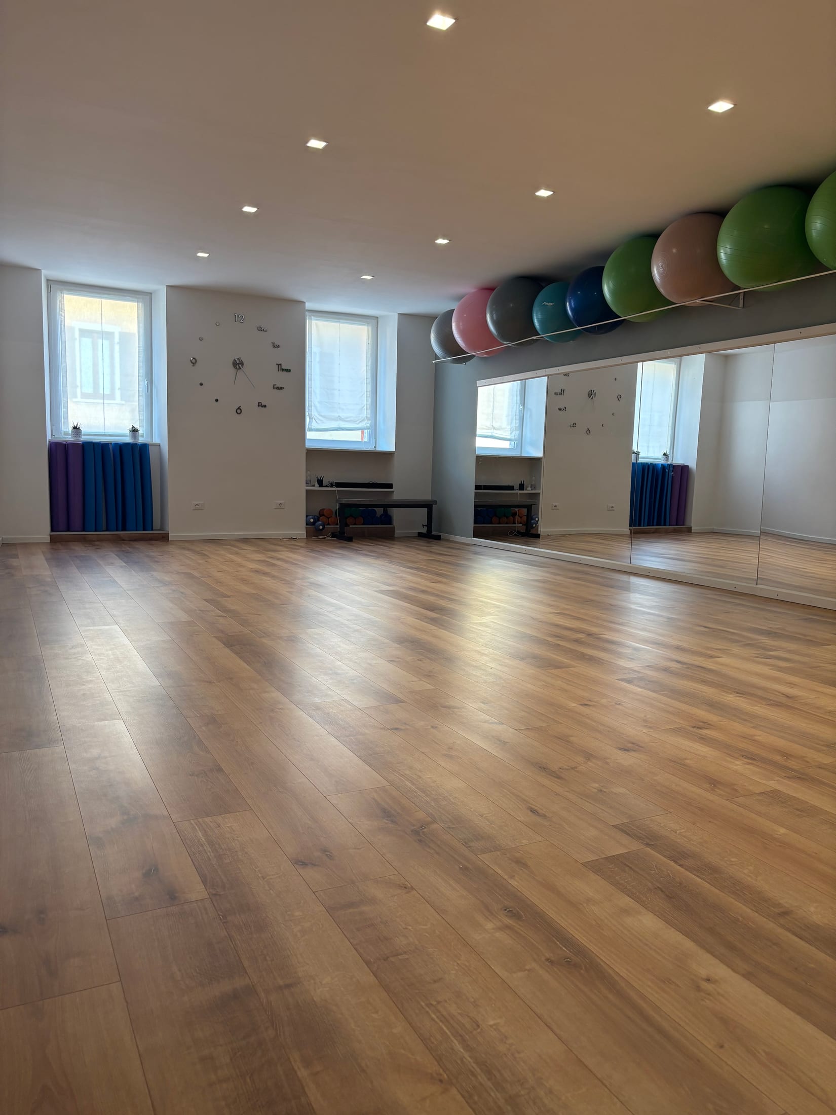 La sala luminosa di Non Solo Pilates con pavimento in legno e parete a specchio